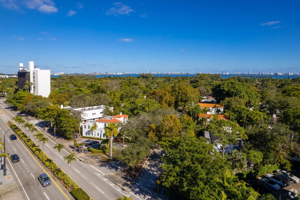 Aerial: Miami streets, tile roofs, downtown and water in the distance.